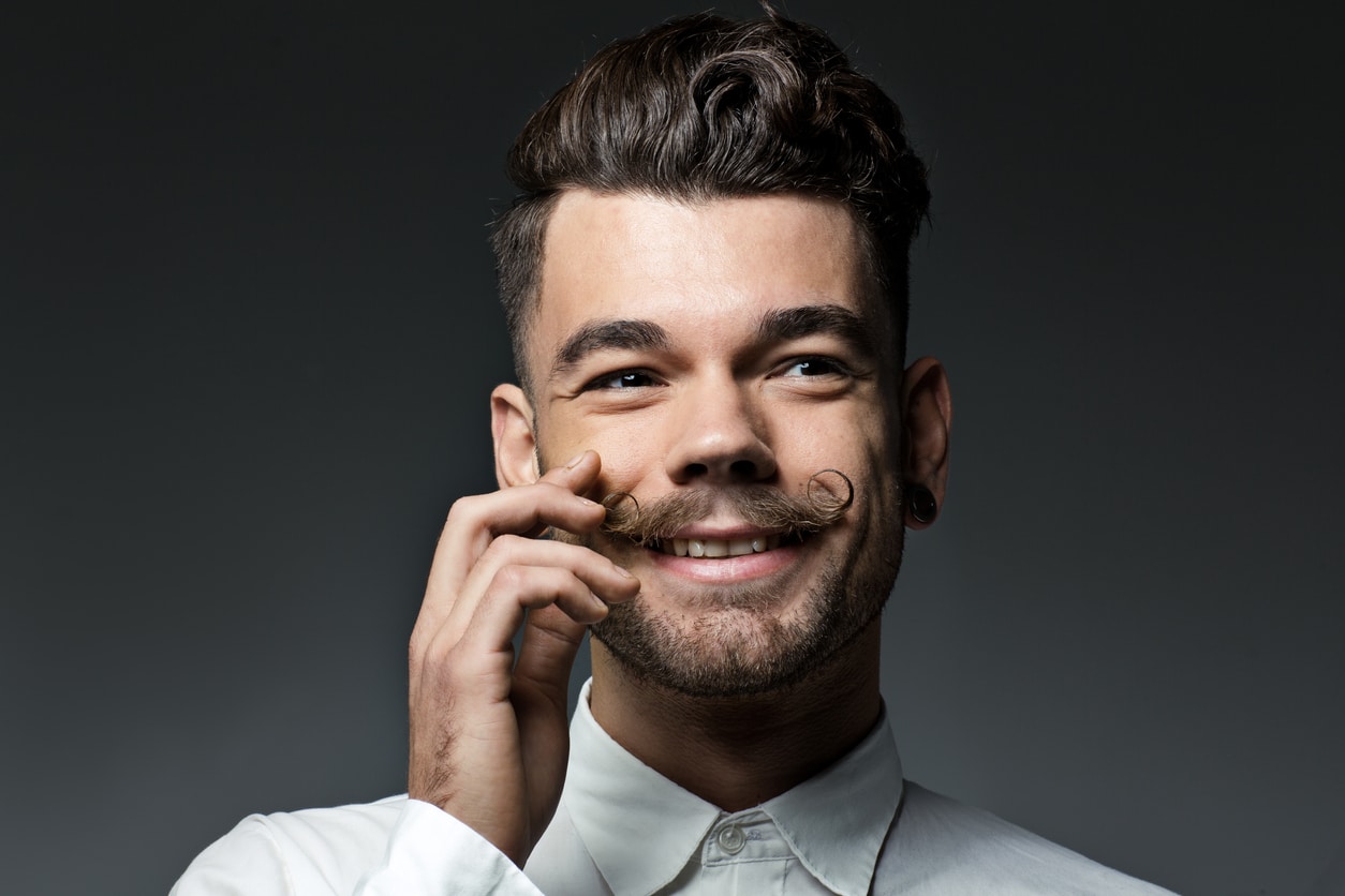 happy young man touching moustache